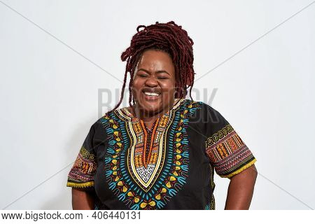 Portrait Of Happy Plump Young African American Woman Lauging With Closed Eyes On Light Background. E