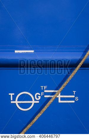 White Plimsoll Mark On Blue Rustproof Steel Hull Surface Of Large Vessel With Mooring Rope In Vertic