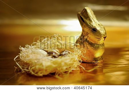 Coniglio di Pasqua di cioccolato e uova su sfondo oro