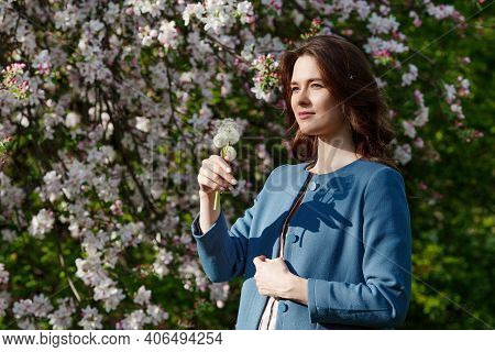 Beautiful Young Woman Holdinh  Dandelion In Spring Garden. Enjoy Nature. Healthy Smiling Girl Outdoo