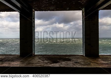 Lookout In Derelict Building Looking Out To Stormy Sea With Two Pillars.