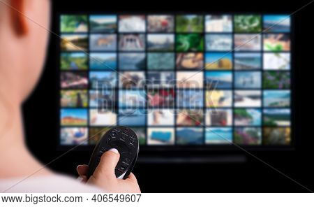 Online Multimedia Video Concept On Tv Set In Dark Room. Woman Watching Online Tv With Remote Control