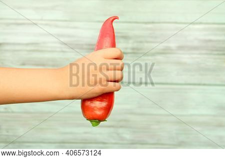 A Teenage Boy Holds A Red Sweet Bell Pepper On A Wooden Background. The Concept Of Agriculture.natur