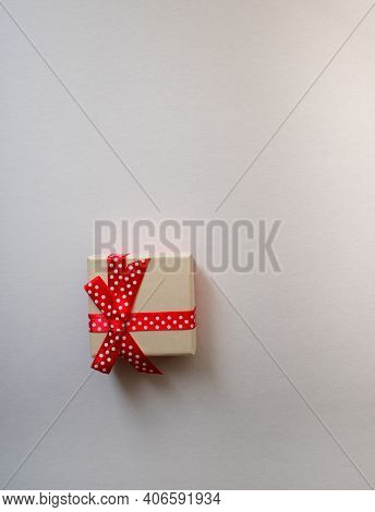 A Small Gift Box With Tied Decorative Bow And Red Ribbon On White Background.holidays Present Concep