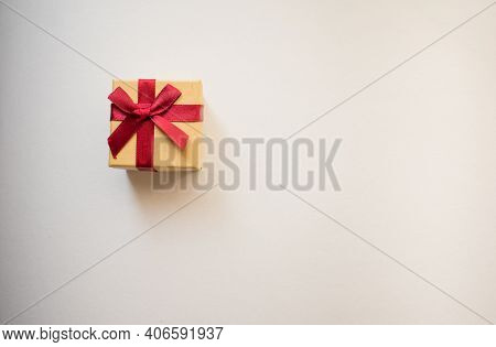 A Small Gift Box With Tied Decorative Bow And Red Ribbon On White Background.holidays Present Concep