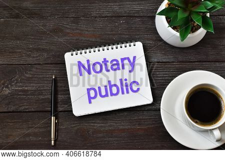 Noteboard With Text Notary Public On A Wooden Background With Pen, Green Plant And Cup Of Coffee . C