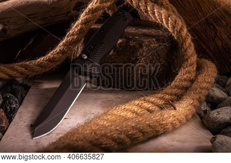 Knife On The Background Of Stones And Rope. Photo Of A Knife With A Great Depth Of Field.