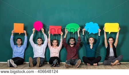 Group Of Six Business People Team Sittiing Together And Holding Colorful And Different Shapes Of Spe