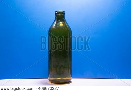 Old Edible Oil Storage Glass Bottle On Blue Background