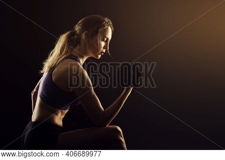 Slim Athletic Woman Holding Dumbbell In The Hand On Black