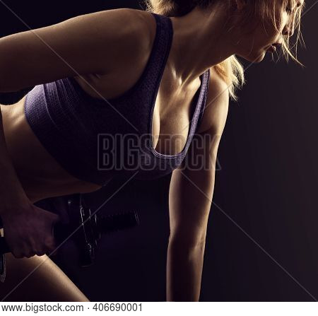 Slim Athletic Woman Holding Dumbbell In The Hand On Black