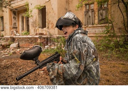 Boy Stands With A Gun In His Hand. Boy In A Gas Mask. \\ra Young Man In A Protective Cloak And Hood.