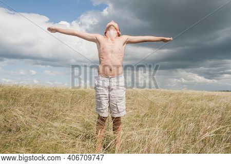 Boy In Shorts Stands In The Field. Boy Looks To The Sky. Dreamer Guy