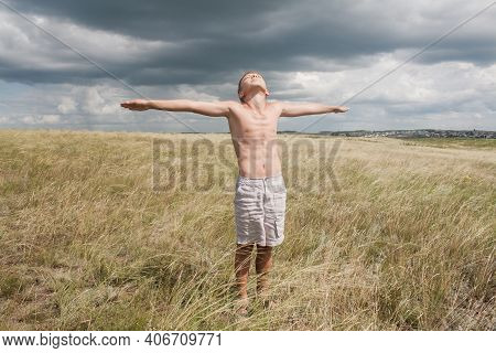boy in shorts stands in the field. boy looks to the sky. dreamer guy