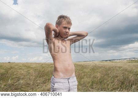 Boy In Shorts Stands In The Field. Boy Looks To The Sky. Dreamer Guy