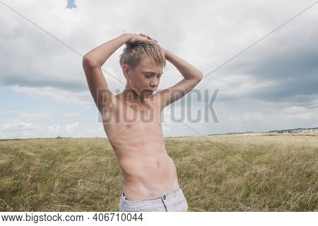Boy In Shorts Stands In The Field. Boy Looks To The Sky. Dreamer Guy