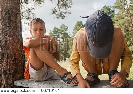Two Boys In Shorts Cross The Road In The Countryside.
