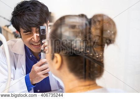 Selective Focus At Optometrist Face. While Doctor Using Penlight And Subjective Refraction To  Exami