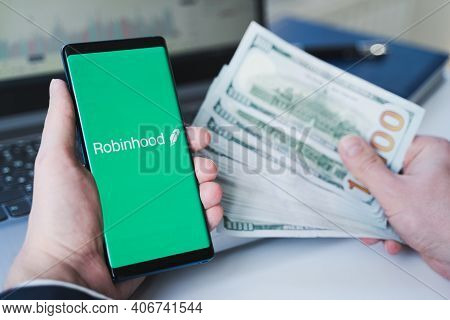Russia Moscow 02.02.21 Mobile Phone With Logo Of Broker Robinhood, Money, Dollars In Hand.financial 