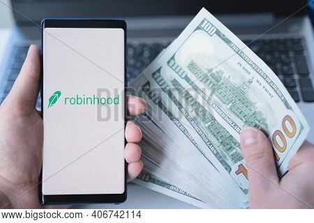 Russia Moscow 02.02.21 Mobile Phone With Logo Of Broker Robinhood, Money, Dollars In Hand.financial 