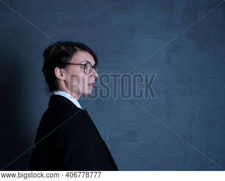 Young Teacher In Glasses On A Black Background In A Jacket