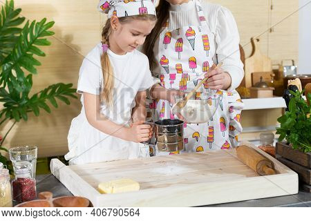 In The Kitchen, Mum Teaches Her Daughter How To Sift Wheat Flour For Pizza Dough. Family Learning In
