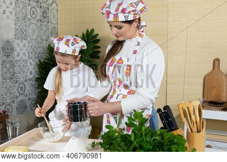 In The Kitchen, Mum Teaches Her Daughter How To Sift Wheat Flour For Pizza Dough. Family Learning In