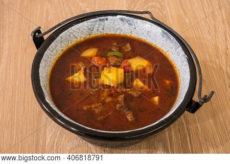 Hungarian Beef Goulash Or Gulyas Soup Or Stew Served In A Small Cauldron With Potatoes, Meat, Paprik