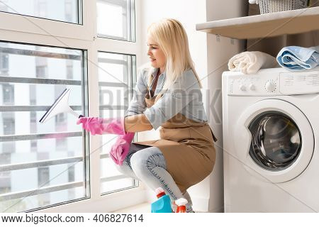 Smiling Black Woman Cleaning Windows With Glass Cleaner