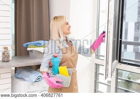 Smiling Black Woman Cleaning Windows With Glass Cleaner