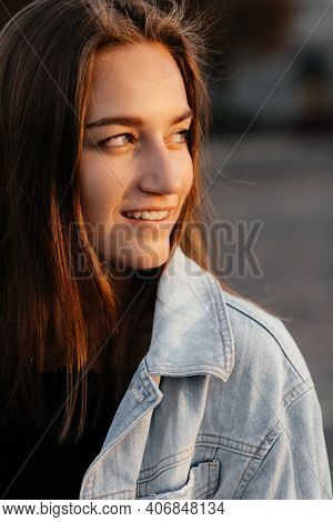 Charming Girl In Jeans Jacket Looking To The Side And Smiling. Girl Portrait