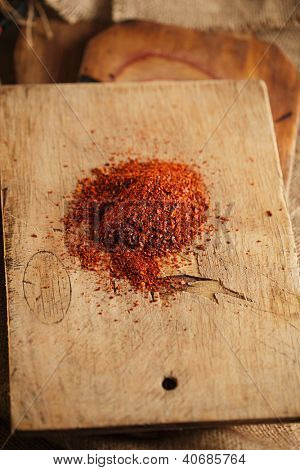 Red hot chilli pepř vločky na dřevěném prkénku pozadí, mělké dof