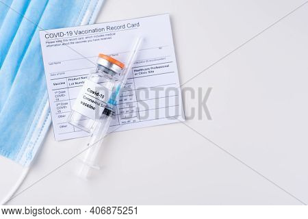 Covid-19 Vaccine Vial, Vaccination Record Card, Syringe, Medical Mask On A White Background, Copy Sp