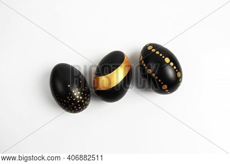 Three Easter Eggs, Fashionably Painted In Black And Gold On A White Background. The Concept Of Minim