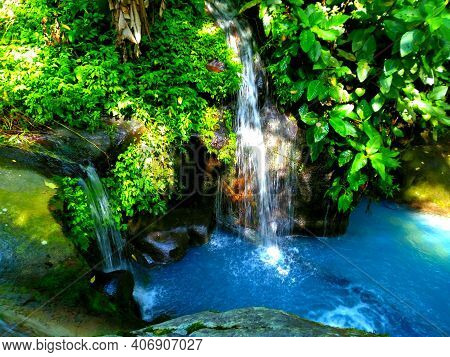 Blue Water That Flows And Falls On The Sidelines Of The Leaves