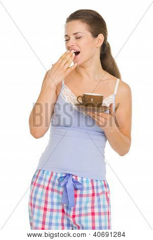 หญิงสาวในชุดนอนด้วยกาแฟ Yawing หลังจากนอนหลับ