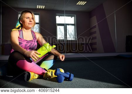 Coach Girl Resting After Workout In The Gym Holding A Green Boot For Water