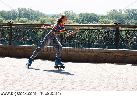 Cheerful Beautiful Teenage Girl Rollerblading In The Park On Awarm Summer Morning