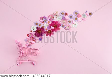 Flowers Fly Out Of The Pink Shopping Cart On A Pink Background. Season Sale, Spring Shoping Concept.