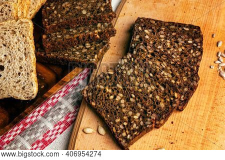 Slices of black rye bread baked with sunflower seeds .