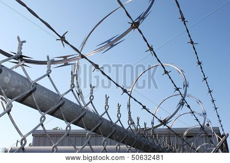 Large metal fence with barbwire and razor wire