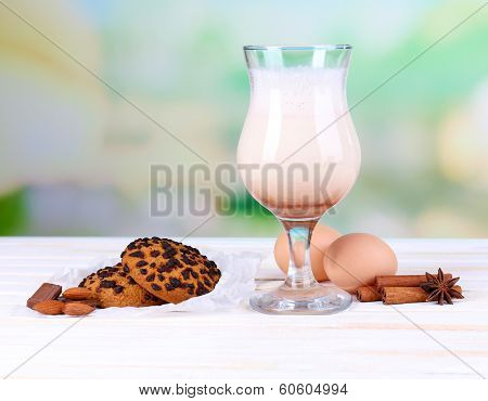 Eggnog with cookies on wooden table and natural background