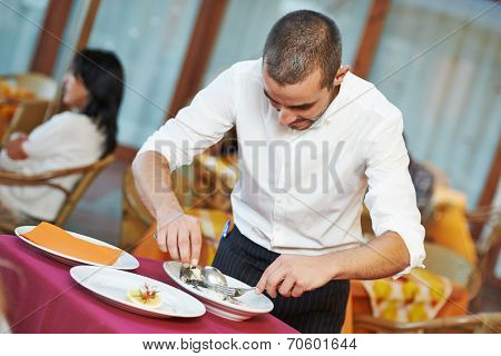 young male waiter prepairing fish food on tray serving at restaurant