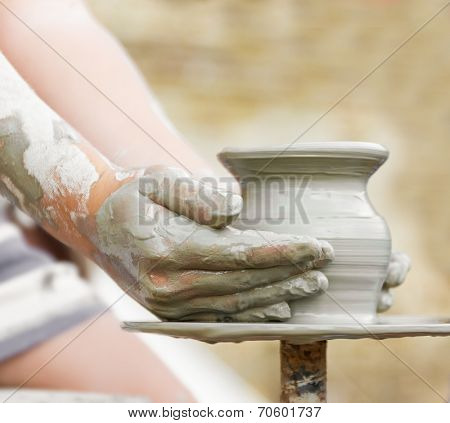 child learning how to make a pot on a pottery wheel, old potter helps
