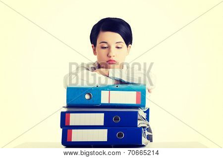 Sad woman with ringbinders sitting at the desk. Tired and exhousted business woman.