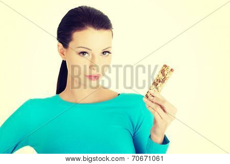 Young woman eating Cereal candy bar, isolated on white