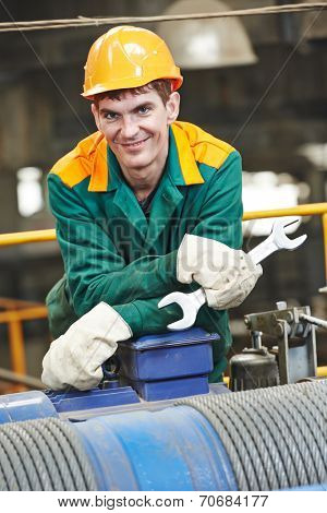 smiling industrial worker with spanner at factory workshop