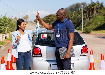 happy african girl and driving instructor doing high five after getting her driving license