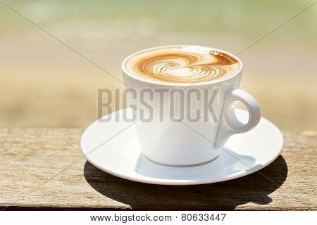 Cappuchino or latte coffe in a white cup with heart shaped foam