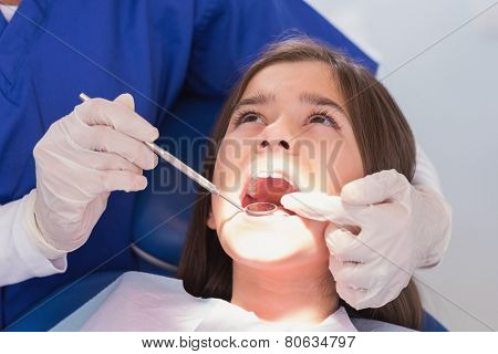 Pediatric dentist examining her young patient in dental clinic